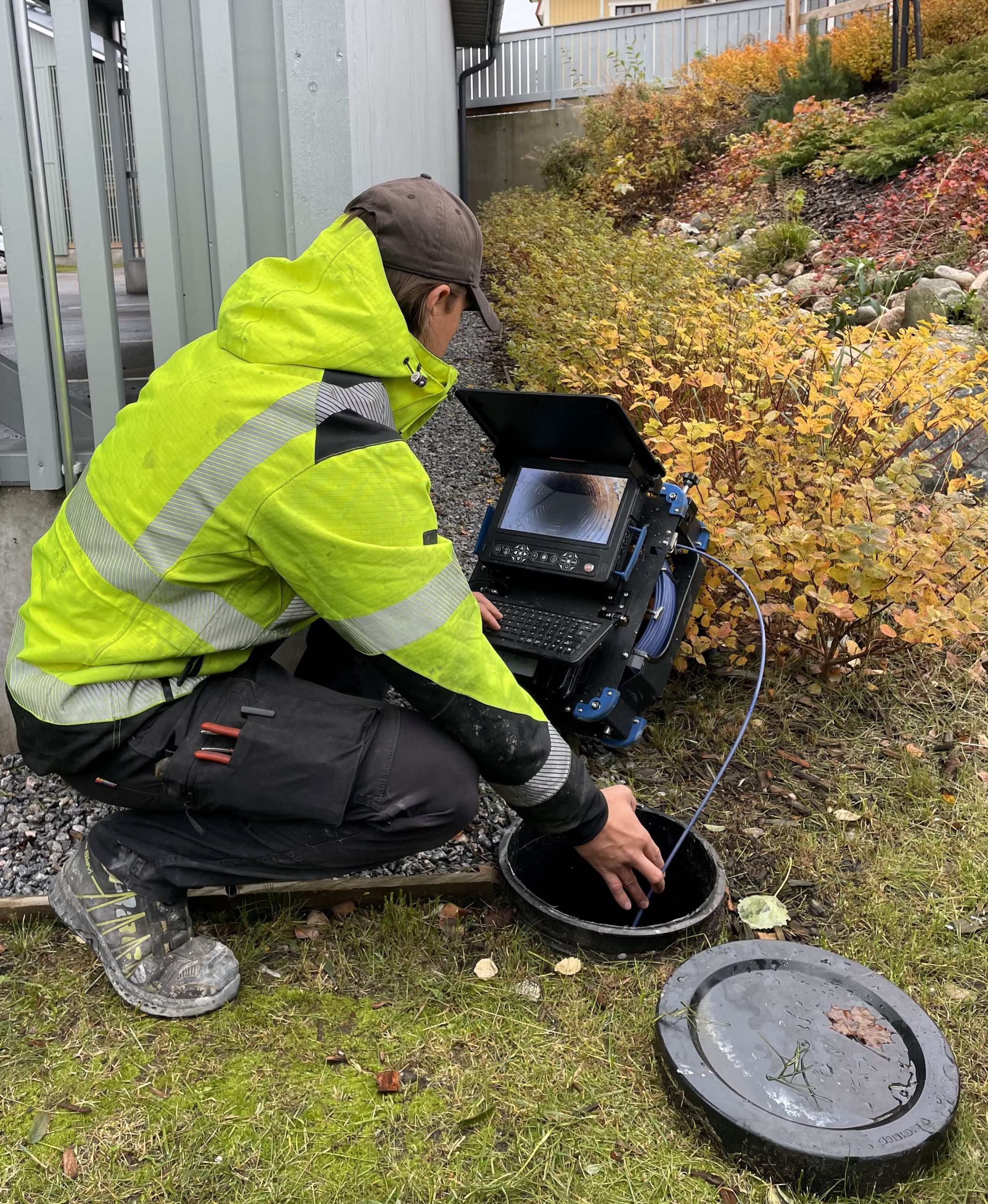 Ammattilainen suorittamassa salaojien kuvausta nykyaikaisella kamerajärjestelmällä pihan tarkistuskaivossa. Kohteessa Vantaa, Uusimaa.