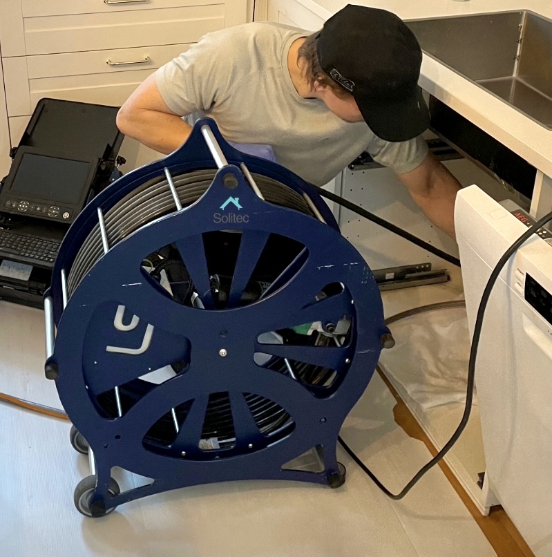 Kuvassa on harjapesulaitteisto ja kuvauslaitteisto ja putkimies suorittaa palveluita viemärikuvaus, viemärihuolto ja viemärin mekaaninen harjapesu. Kuvattu kohteessa paikkakunnalla Helsinki.